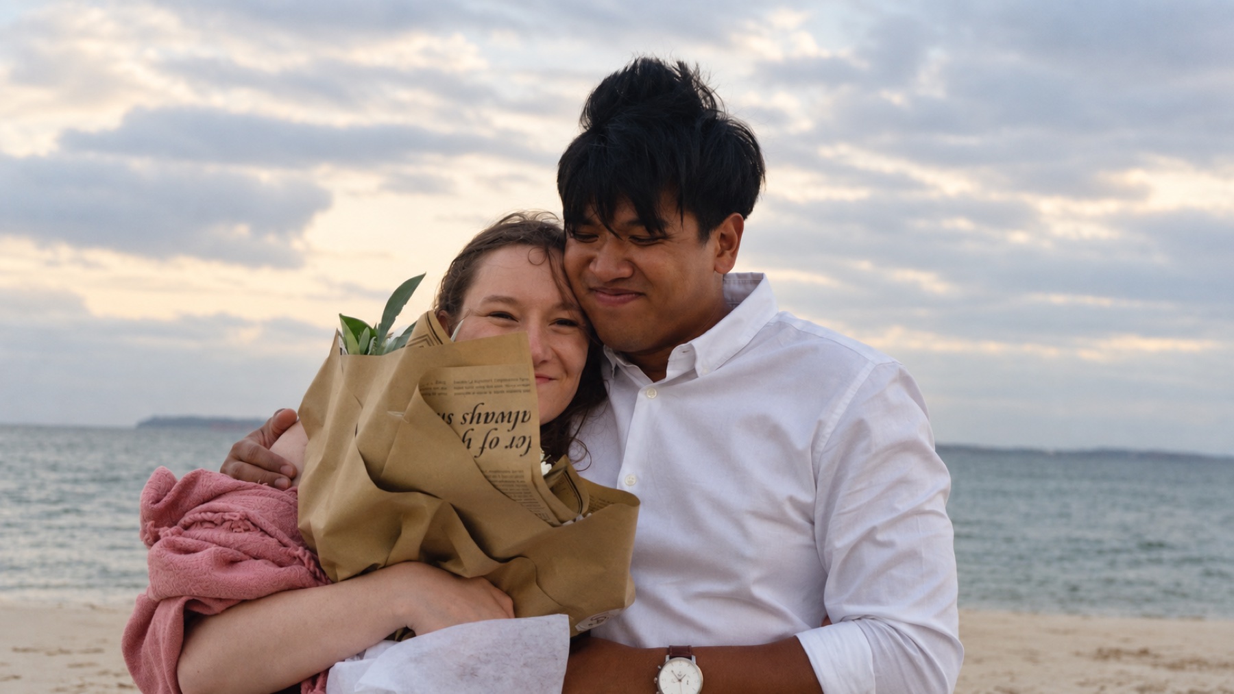 Grace and Franz embracing on the beach at sunset